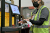 A warehouse worker for Superior Uniform Group scans a shipment label on a collaborative mobile robot from 6 River Systems at a facility in Coppell, Texas.